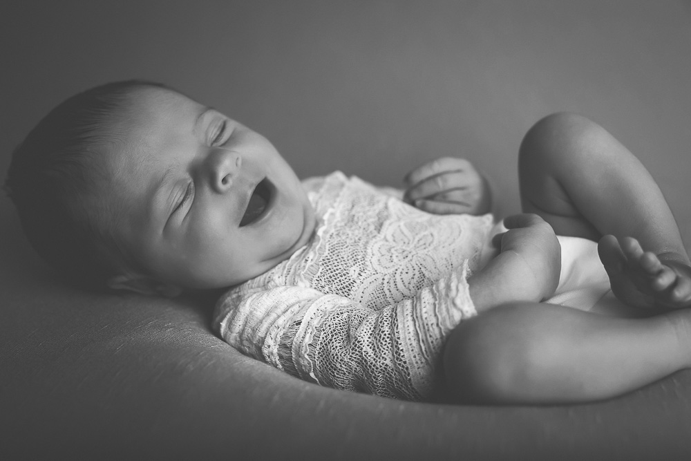 Baby lacht im Schlaf beim Neugeborenenshooting.